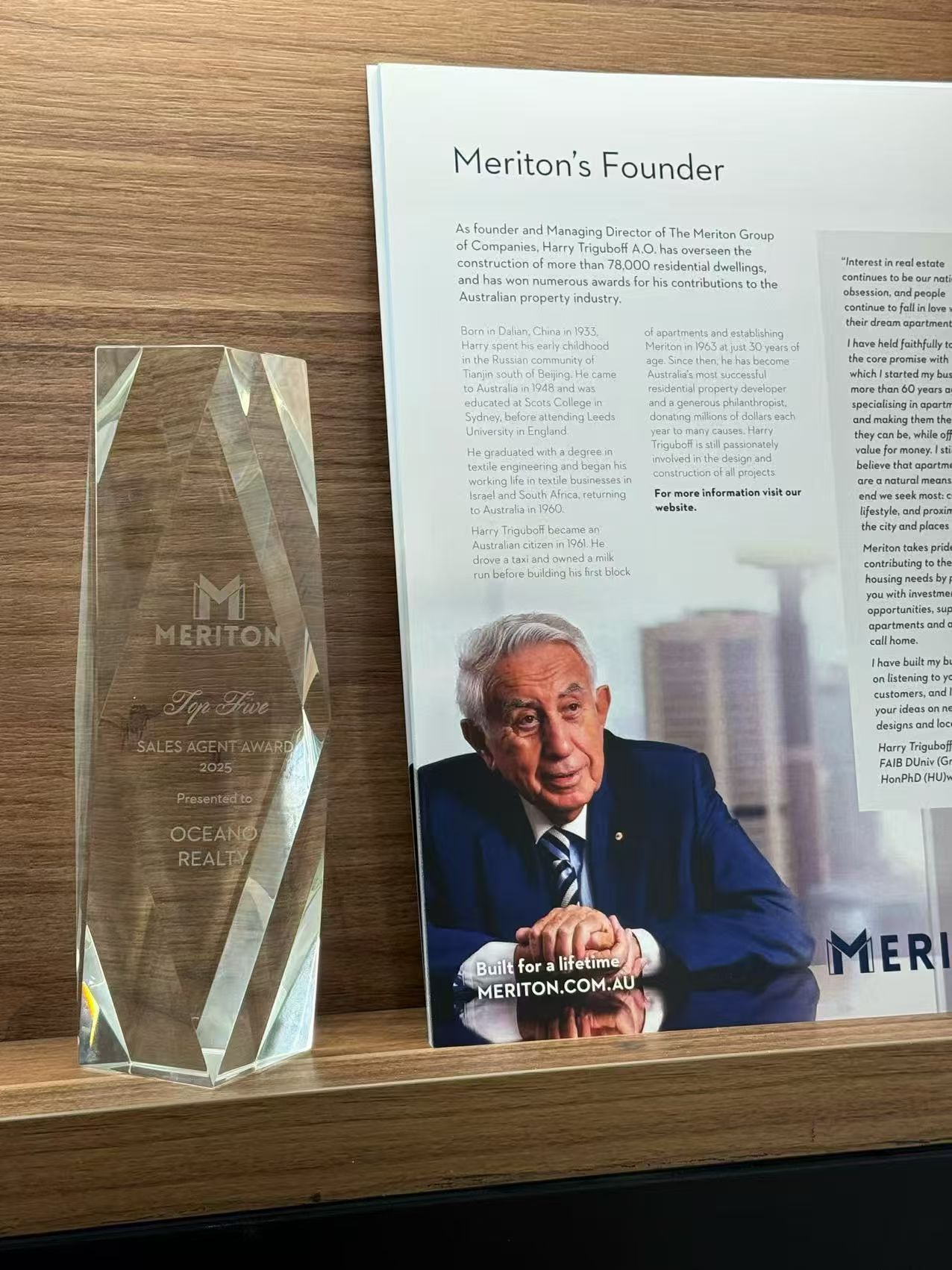 Meriton Top Sales Agent award trophy, presented to Oceano Realty, beside a profile of Meriton founder Harry Triguboff